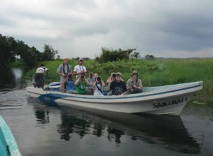 Birders in a boat with binoculars and cameras.