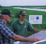 Two men in a wetland looking at a map together.