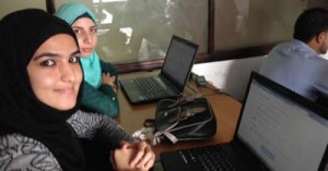 Two women at a desk with laptops.