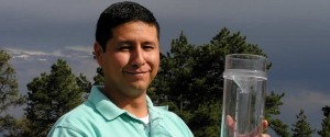 A man outside holding a large rain gauge.