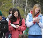 Three students writing in journals outside.