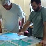 Two men standing at a table looking at a map.