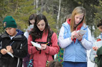 Three students writing in journals outside.