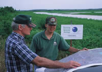 Two men in a wetland looking at a map together.