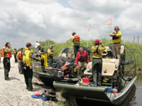 A group of U.S. Fish and Wildlife Service firefighters and the production crew of a Discovery Channel show preparing to ride two airboats.